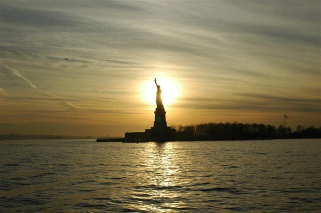 Sun behind Statue of Liberty