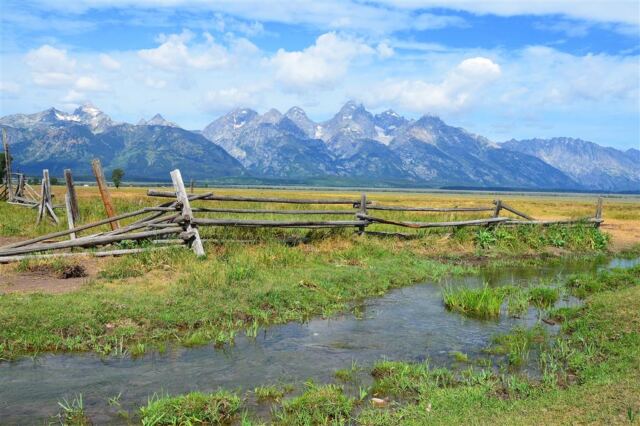 Stream, fence, and Tetons